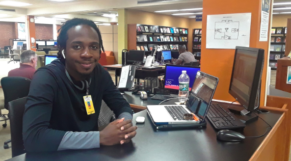 Brian Huyghue, first-year graduate, working the Information Desk in the library. Photo by Debra Born.