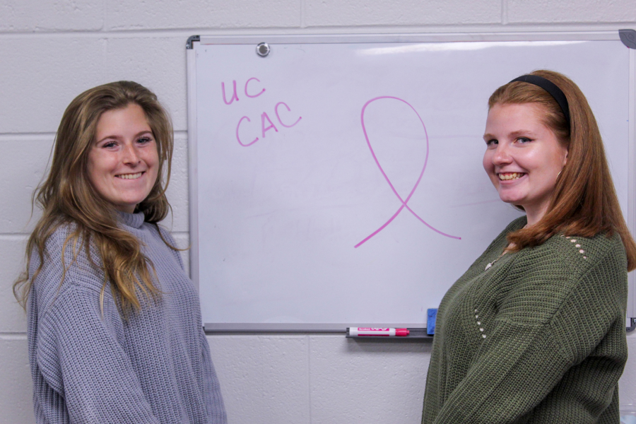  Liz Gabel (left), president of Colleges Against Cancer (CAC) and Casey Hourican, vice president, pose by a symbol of breast cancer awareness in the CAC office. Photo by Debra Born. 