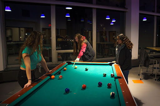 From left, Leola Beck '25, Karrie Kosier '25 and Lila Vega '25 during their nightly game of pool.
"If commuter students want this part of the college experience, they should be able to experience it," Beck said.