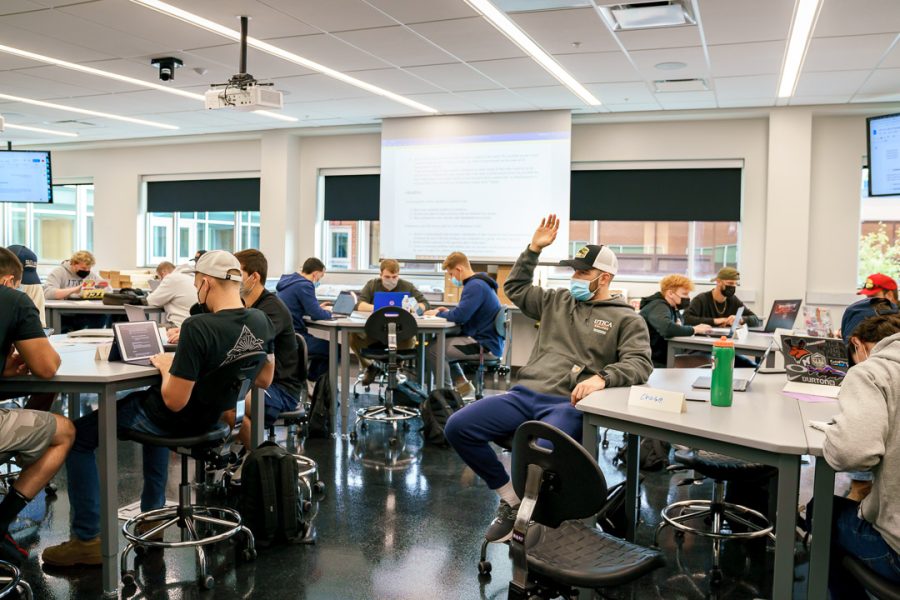 A student raises their hand in the middle of a Fall 2021 class when masks were required.