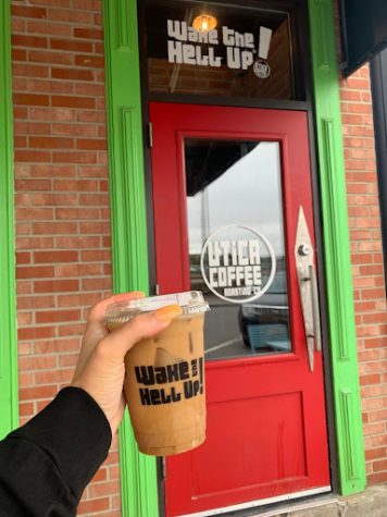 A fresh iced coffee in front of the doors of Utica Coffee. 