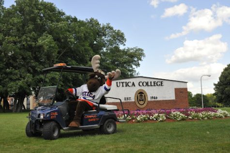 Trax taking the Campus Safety Cart for a joy ride in front of the Utica College sign.