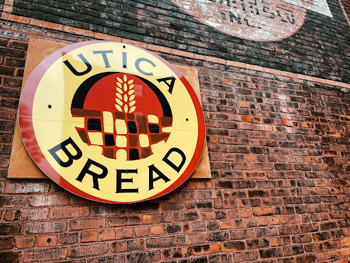 Utica Bread’s logo mounted on the wall next to the Bagg's Square Location.