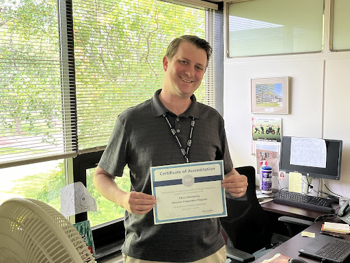 Kyle Riecker holding the AAQEP Certificate of National Accreditation for the Utica University Educator Preparation Program