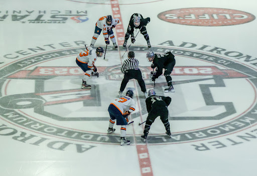 Three Utica men's ice hockey players square up at center ice.