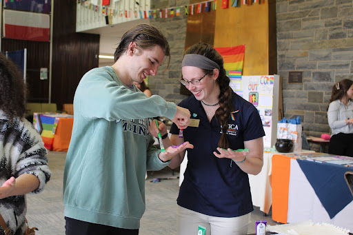 Two attendees from the Coming Out Day event painting each other's hands. 
